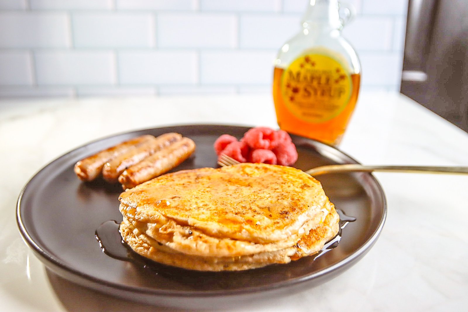 Protein pancakes on black plate with sausage and raspberries